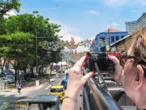 woman taking photos from top of sightseeing bus